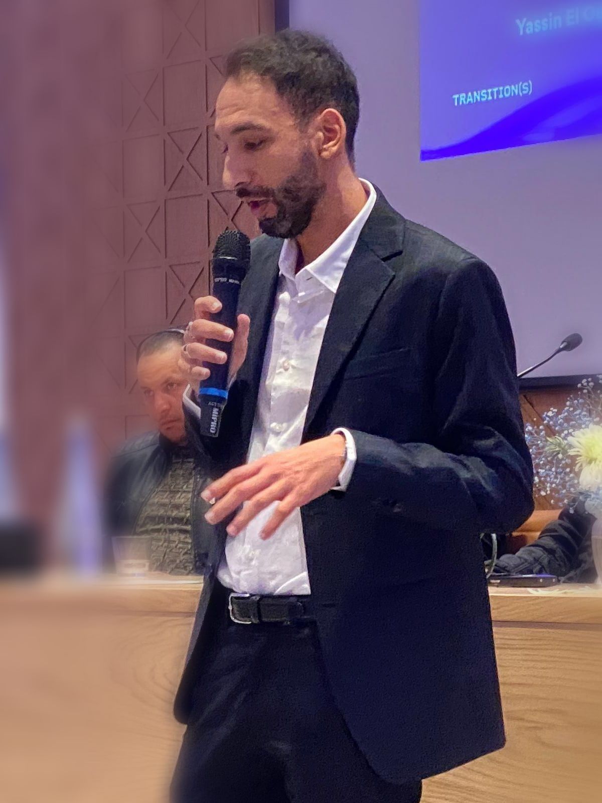 Yassin Elouardi speaking with a microphone at a conference panel.